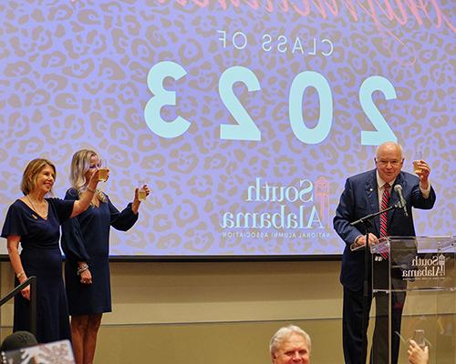 President Bonner, Vice President Kent, and Margaret Sullivan holding up champagne glasses to toast the class of 2023.